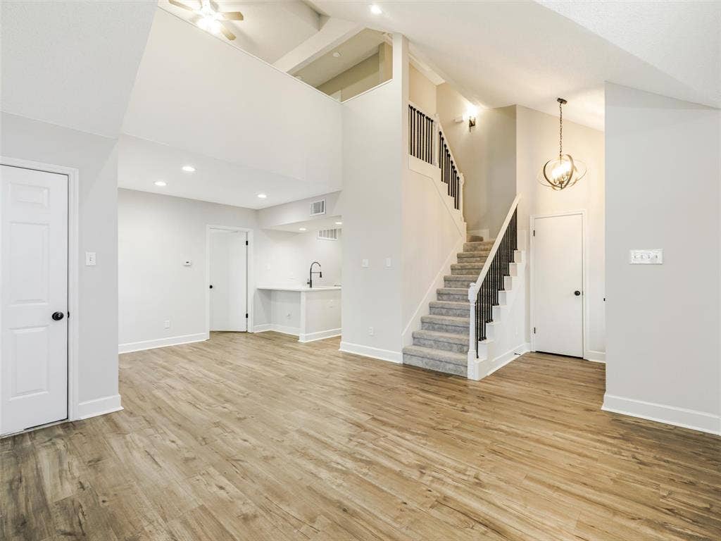 449 Harris Street, #102L, Coppell, TX 75019 Vaulted ceilings with recessed lighting, wood-finish flooring, staircase with a matte black railing, orb-style pendant lighting, and an integrated wet bar