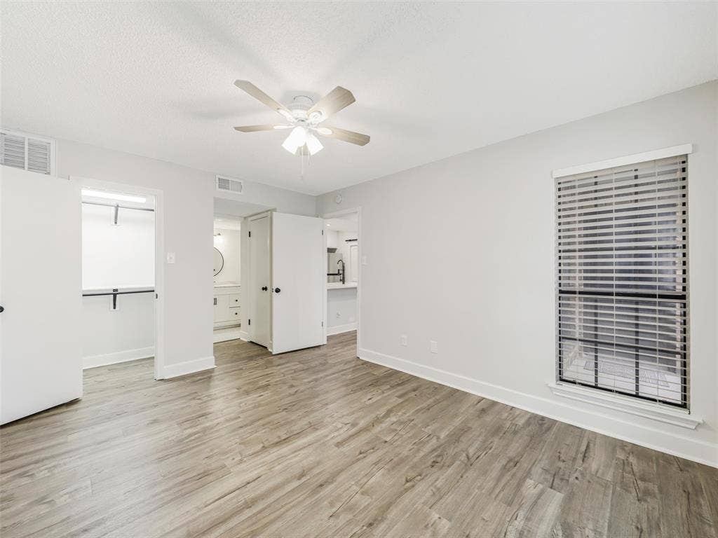 449 Harris Street, #102L, Coppell, TX 75019 Room featuring wood-finish flooring, a ceiling fan with integrated lighting, a window with horizontal blinds, and built-in closet shelving