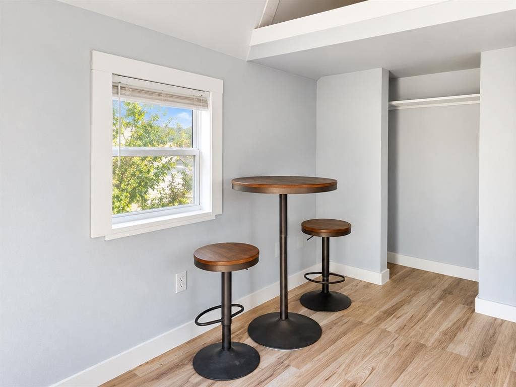 Wood-finish flooring, neutral wall tones, single-hung window with wide white trim, and a built-in recessed closet area with a fixed shelf