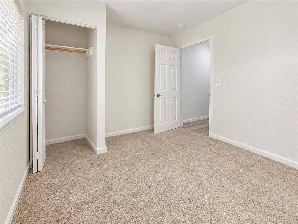 Neutral-toned interior featuring wall-to-wall carpeting, a reach-in closet with folding doors, and a six-panel interior door