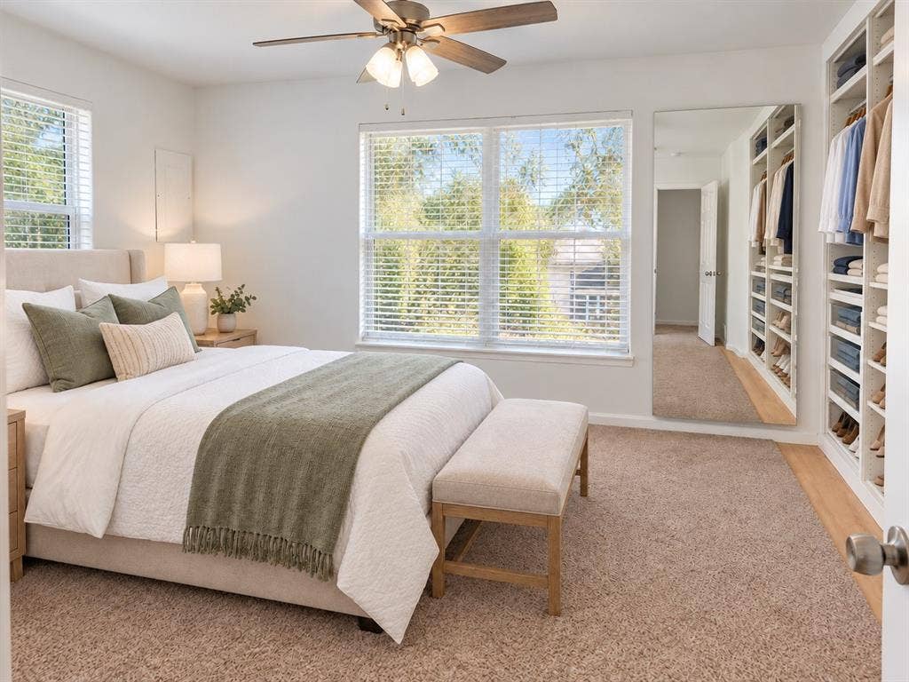 Bedroom featuring wall-to-wall carpeting, custom built-in shelving, a full-length wall mirror, and a ceiling fan with integrated lighting