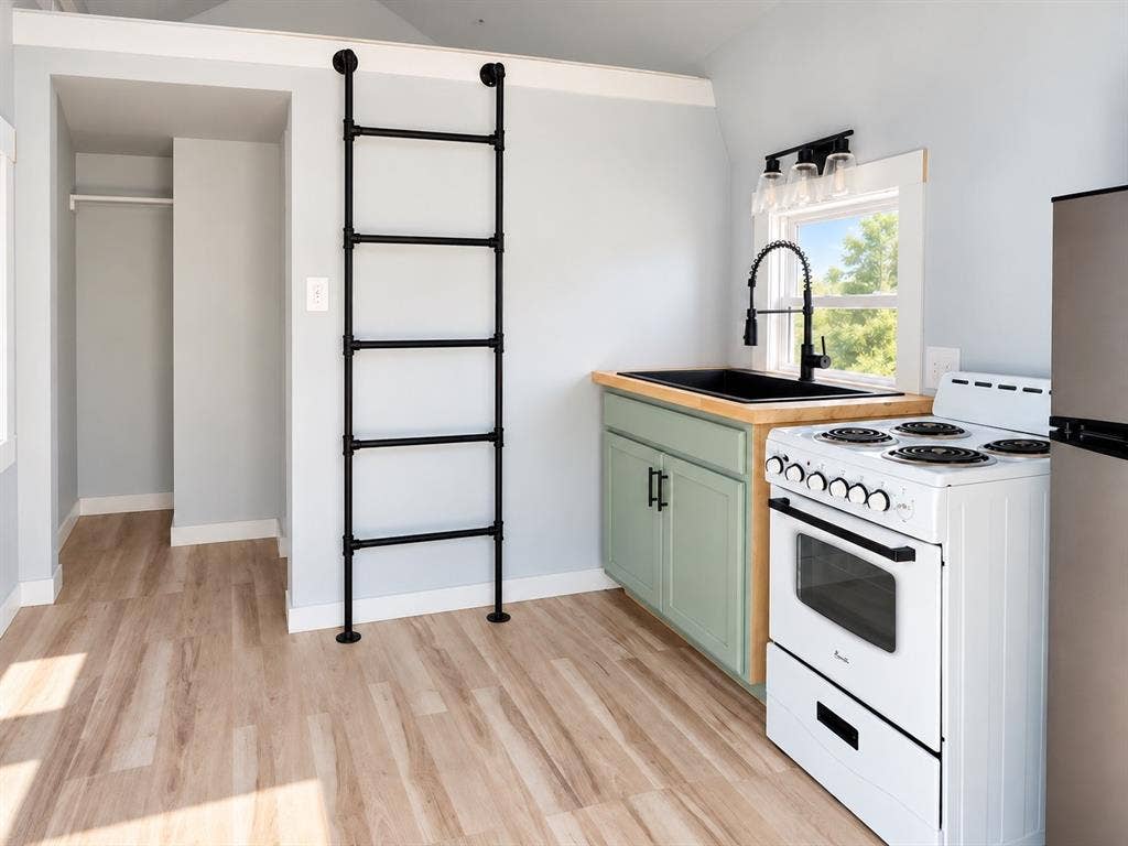 Kitchen featuring wood-finish flooring, cabinetry with matte black hardware, a wood countertop, a black drop-in sink with a high-arch pull-down faucet, and a floor-to-ceiling iron pipe ladder