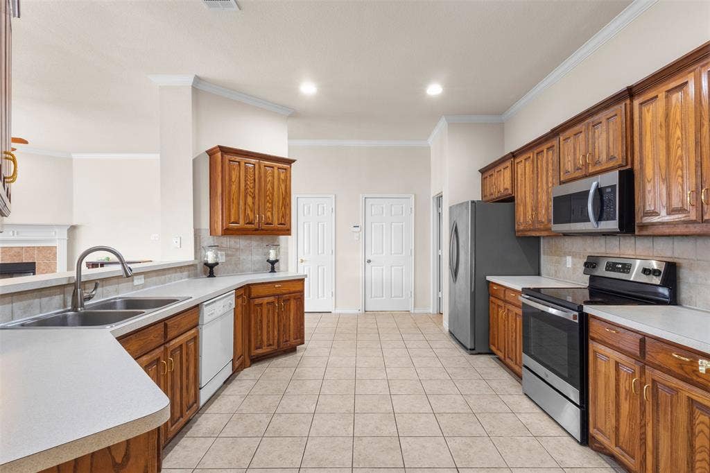 Kitchen featuring stained wood cabinetry, solid surface countertops, tile flooring, recessed lighting, and stainless steel appliances