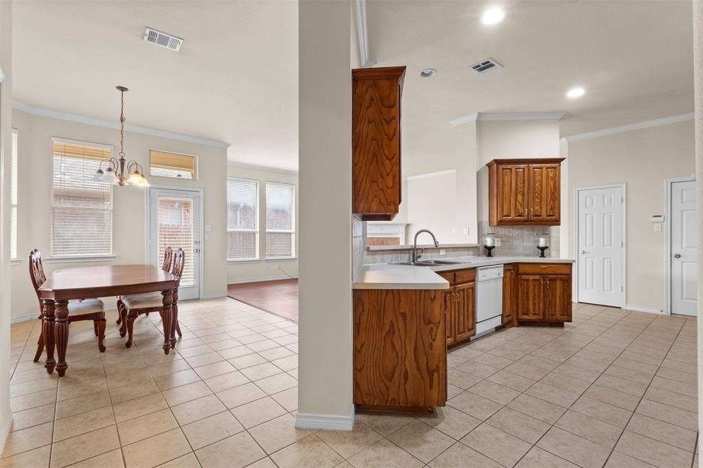 Kitchen featuring stained wood cabinetry, solid surface countertops, and white appliances, complemented by tile flooring and crown molding