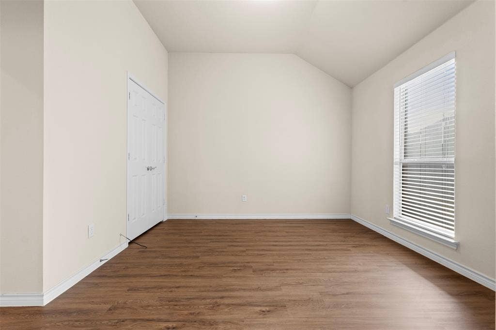 Room featuring wood-finish flooring, vaulted ceilings, and a double-door closet