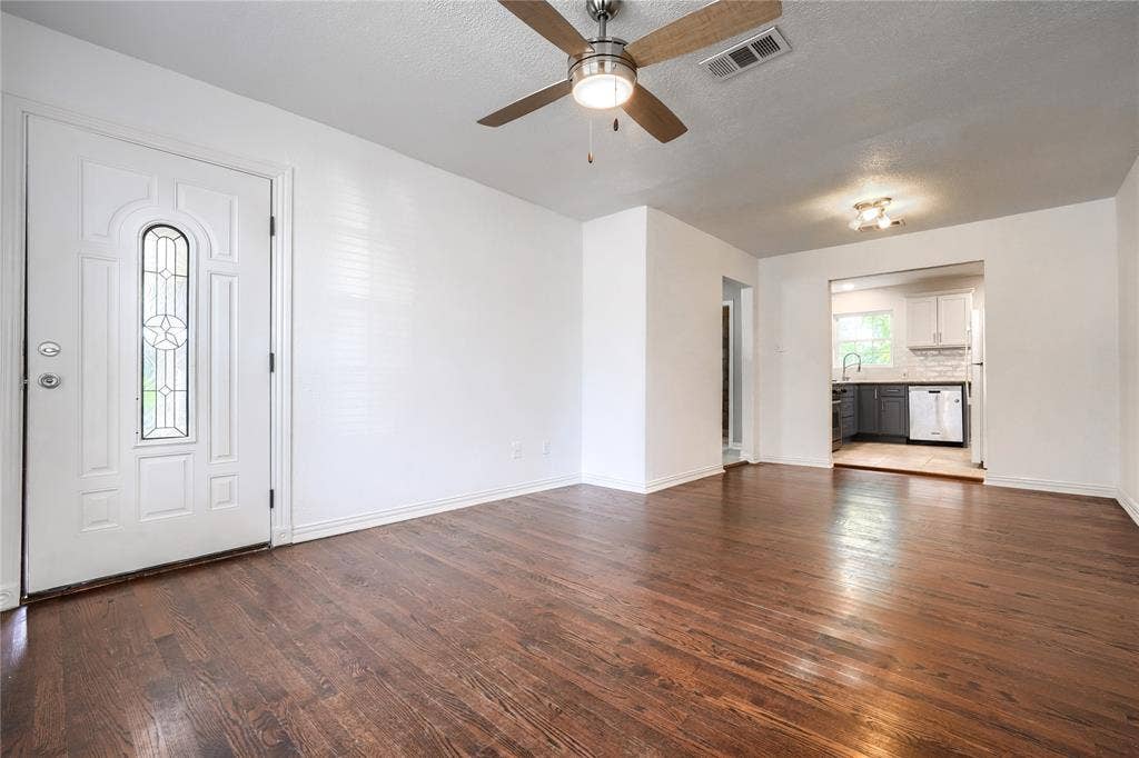 Interior space featuring wood-finish flooring, white walls, and a ceiling fan with integrated lighting