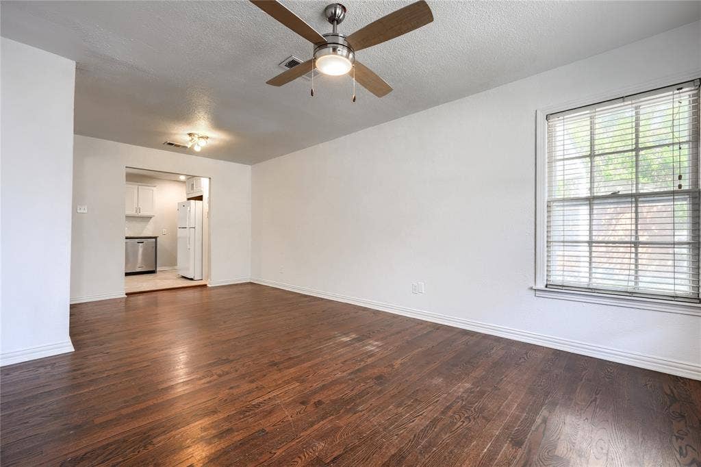 Wood-finish flooring, neutral wall tones, multi-pane window with blinds, and brushed-metal ceiling fan with integrated light fixture