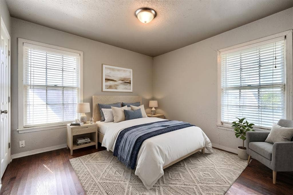 Room with wood-finish flooring, two large windows with horizontal blinds, and a circular flush-mount ceiling light fixture