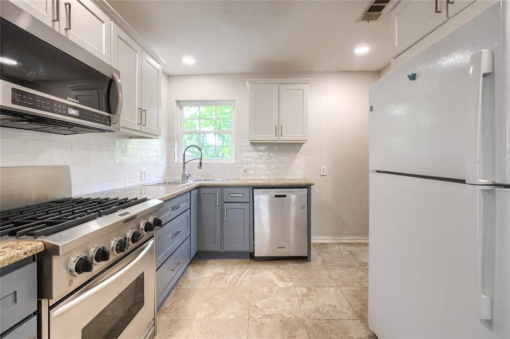 Kitchen featuring stone-finish countertops, subway tile backsplash, stainless steel gas range, built-in dishwasher, and stone-finish flooring