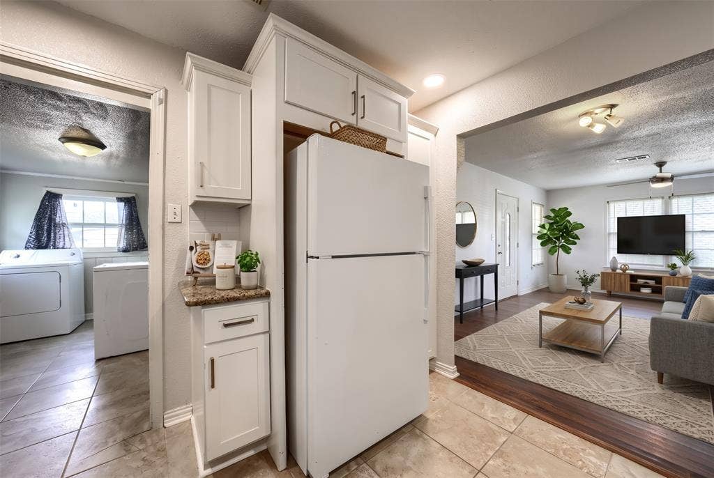White cabinetry with metal hardware, stone-surface countertop, and ceramic tile flooring