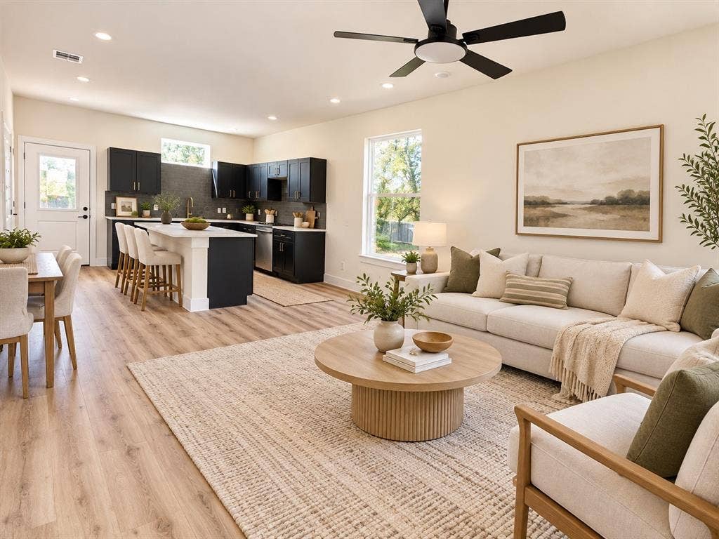 Open-concept living space featuring wood-finish flooring, recessed lighting, matte black ceiling fan, dark cabinetry with a central kitchen island, and white solid-surface countertops