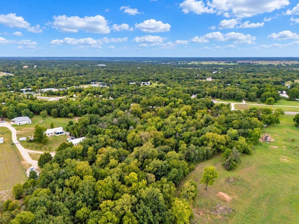 Expansive acreage featuring mature tree lines, open pasture land, and paved driveways