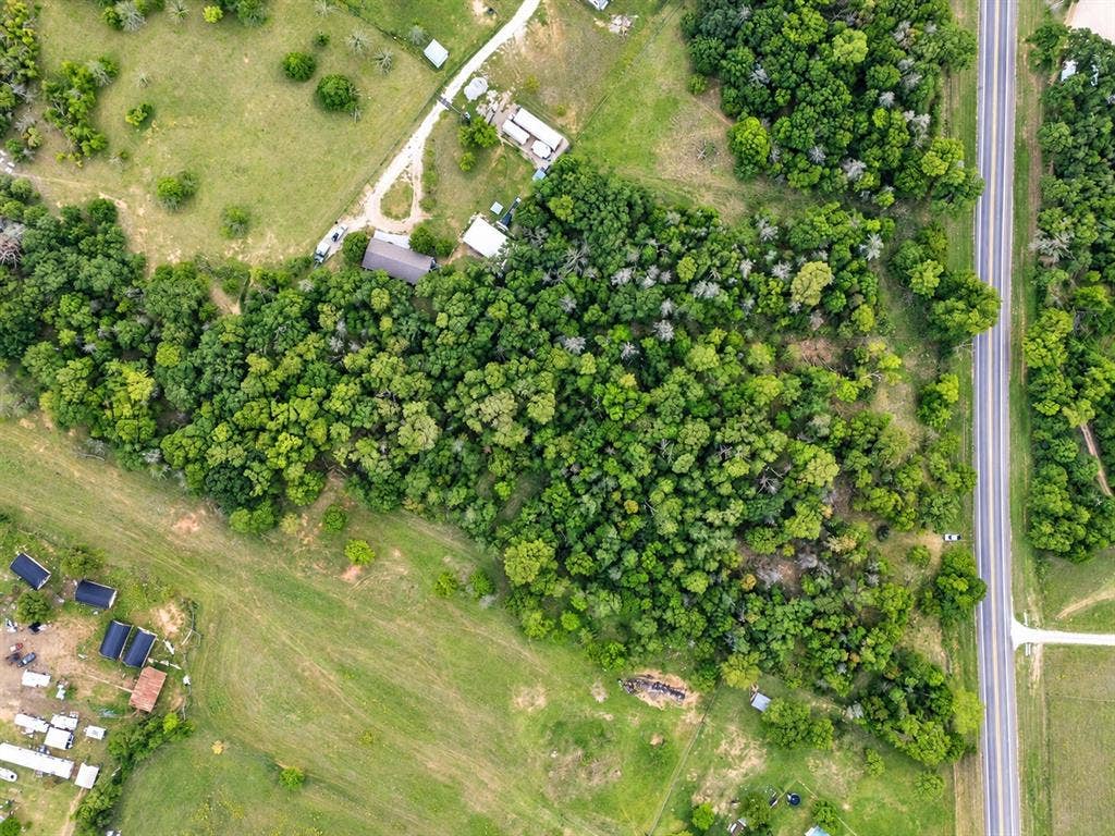 Expansive land parcel featuring mature forest coverage, rolling grass acreage, and direct road frontage