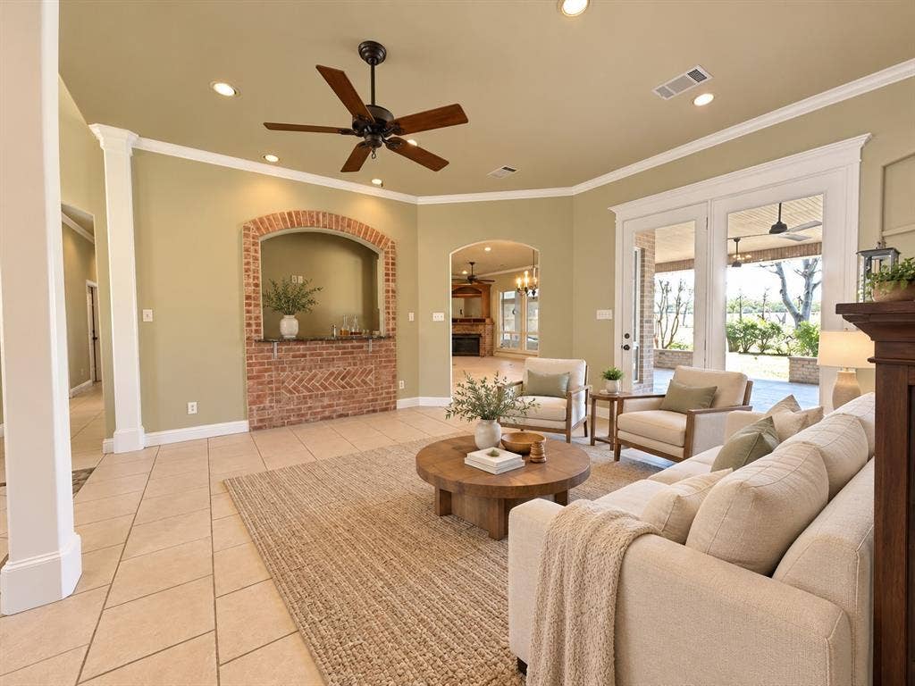 Living area featuring tile flooring, recessed lighting, a ceiling fan, a brick-surround built-in alcove, and multi-pane glass doors