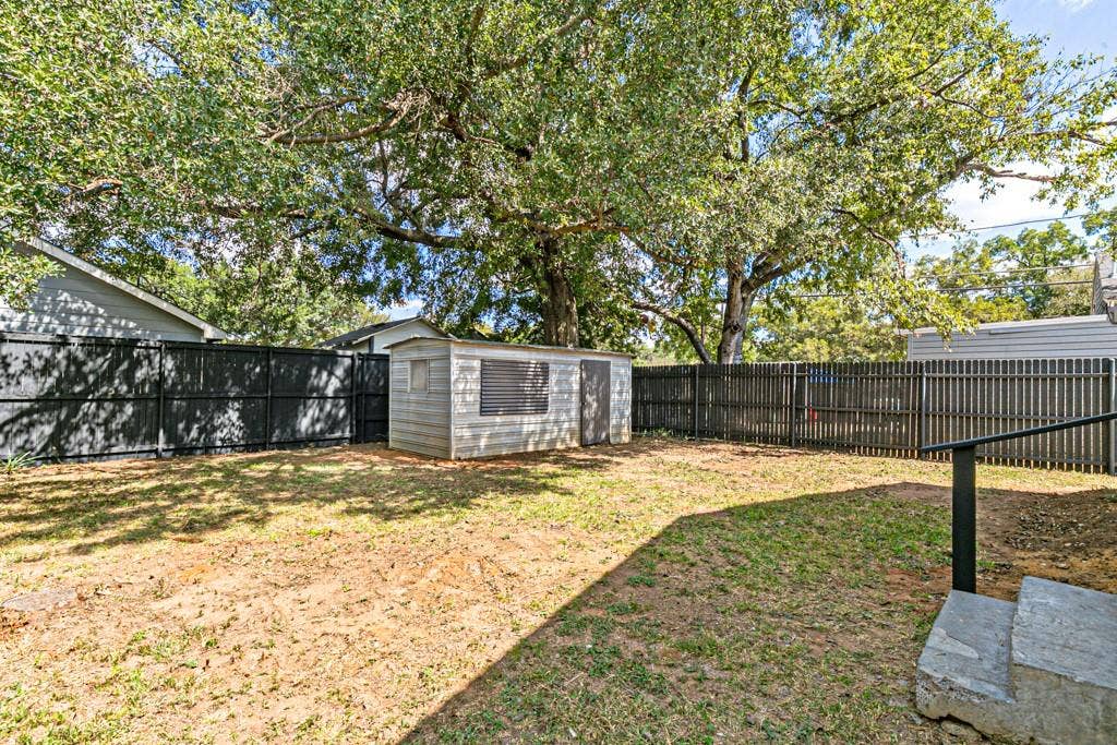 5140 Dimple Jackson Street, Dallas, TX 75210 Spacious, fenced backyard with mature shade trees and a convenient storage shed.