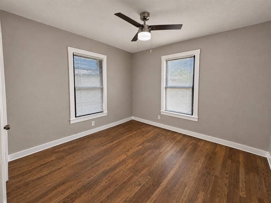 5140 Dimple Jackson Street, Dallas, TX 75210 Bright bedroom featuring two windows, wood flooring, and a ceiling fan.