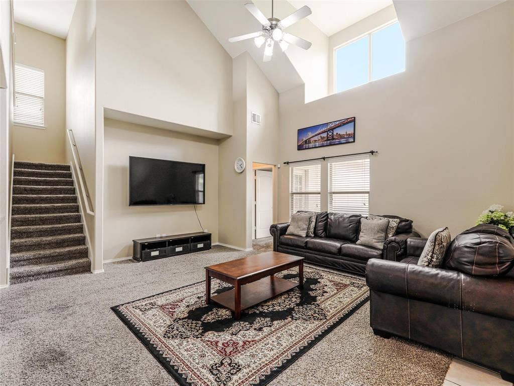 9720 Tipperary Drive, McKinney, TX 75072 Vaulted ceilings, expansive windows, carpeted staircase with metallic handrail, and integrated ceiling fan with lighting fixture