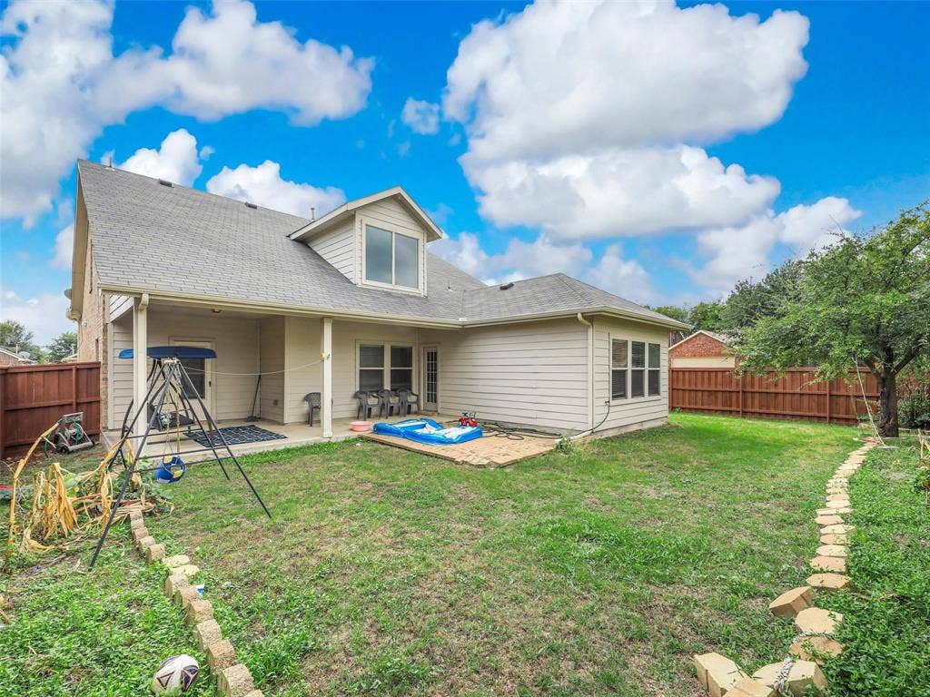 9720 Tipperary Drive, McKinney, TX 75072 Rear exterior featuring a covered patio, paved stone walkway, and full perimeter wood fencing