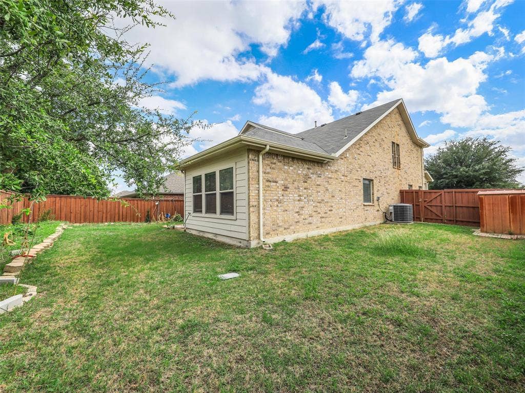 9720 Tipperary Drive, McKinney, TX 75072 Exterior backyard space featuring a brick and siding facade, wood privacy fencing, and mature trees