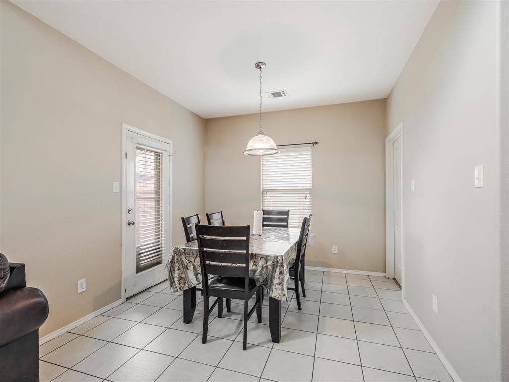 9720 Tipperary Drive, McKinney, TX 75072 Dining area featuring large-format ceramic tile flooring, a brushed-nickel pendant light fixture, and a glass-paneled exterior door