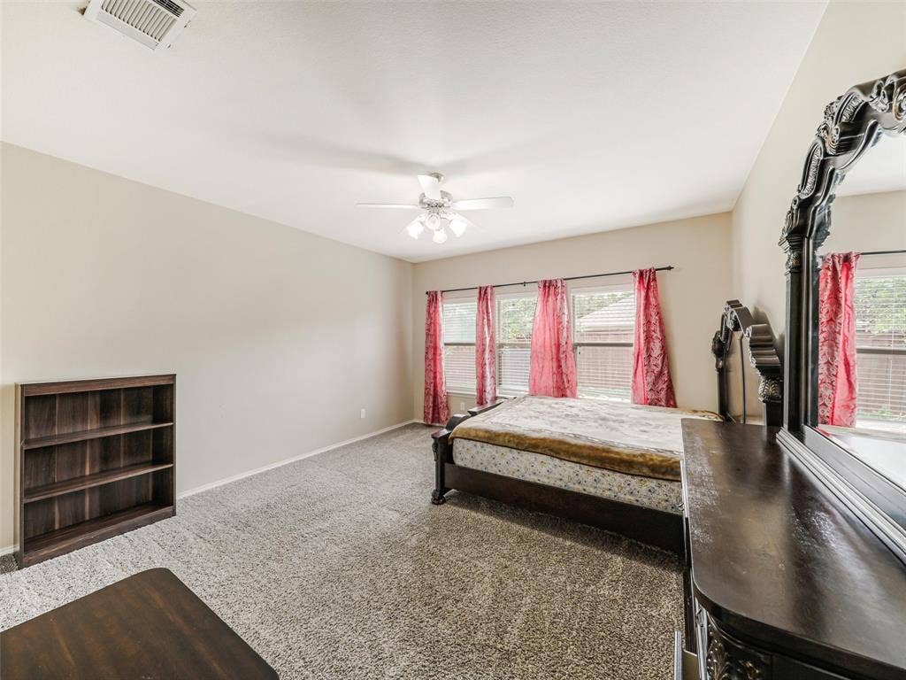 9720 Tipperary Drive, McKinney, TX 75072 Neutral-toned room featuring wall-to-wall carpeting, multiple windows with natural lighting, and a ceiling-mounted light fixture with a fan