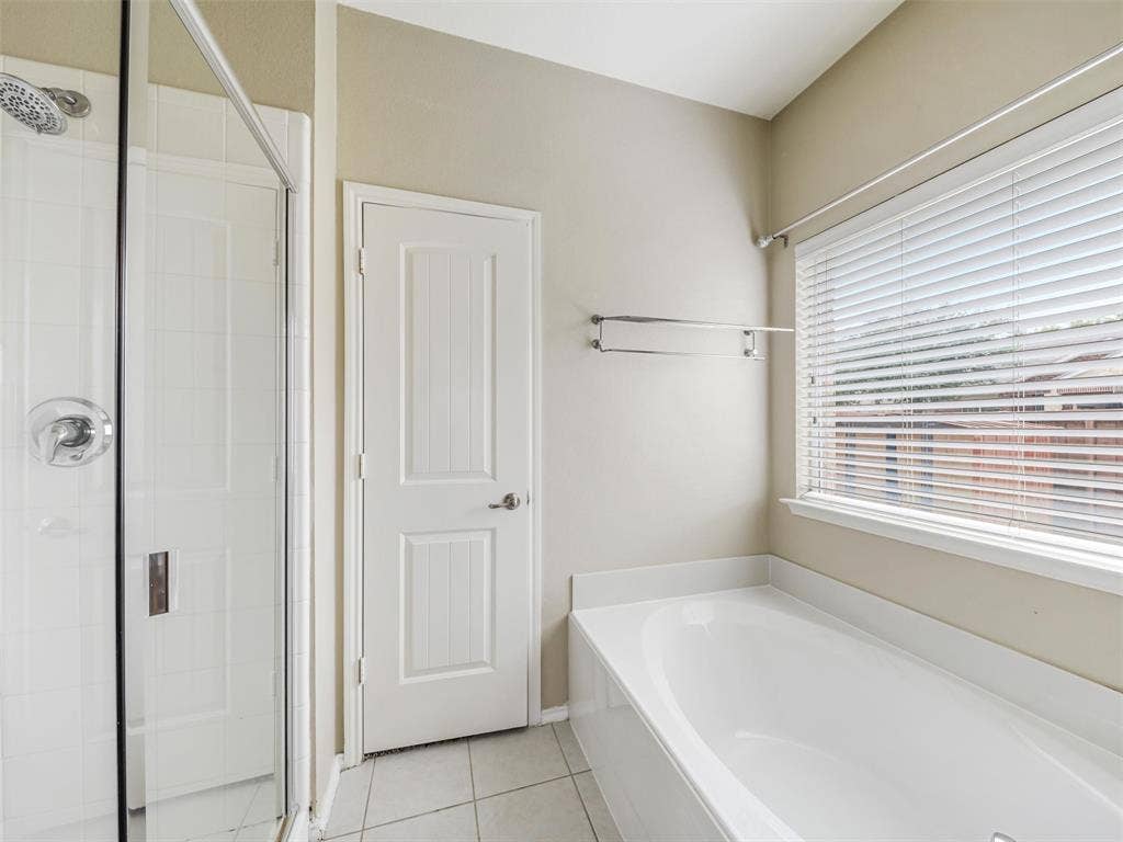 9720 Tipperary Drive, McKinney, TX 75072 Walk-in shower with chrome hardware, soaking tub with tile surround, and horizontal window blinds