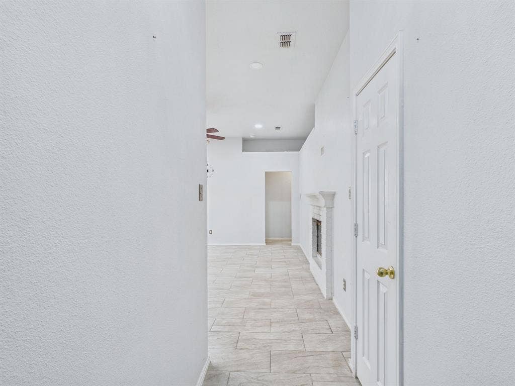 Neutral-toned tile flooring, recessed lighting, and a fireplace with a decorative mantel featuring a classic surround