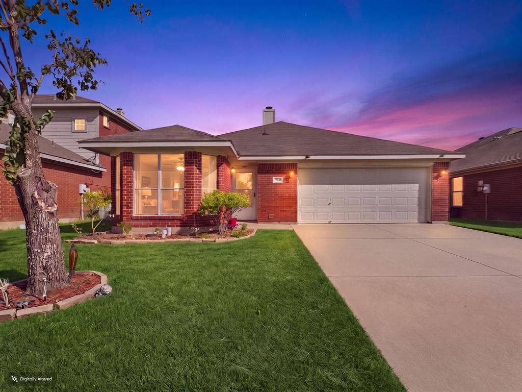 Single-story residence featuring a brick exterior, prominent bay window, two-car garage, concrete driveway, and professional landscaping