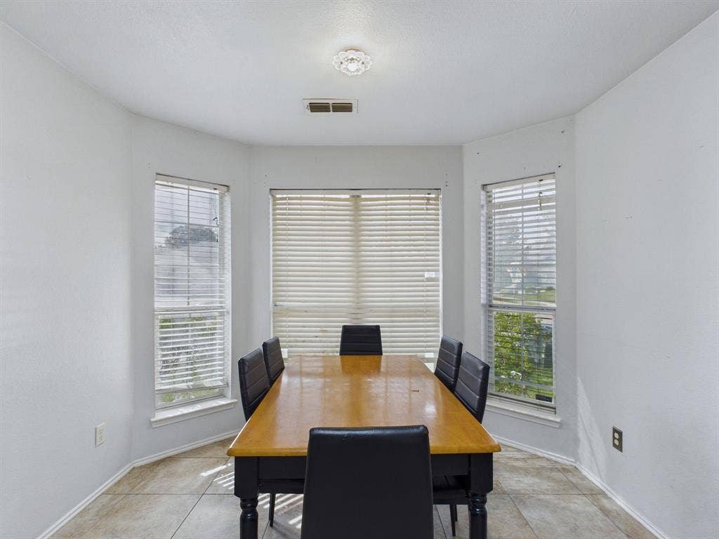 Bay window featuring neutral tile flooring, multi-pane windows with horizontal blinds, and a central flush-mount ceiling light fixture