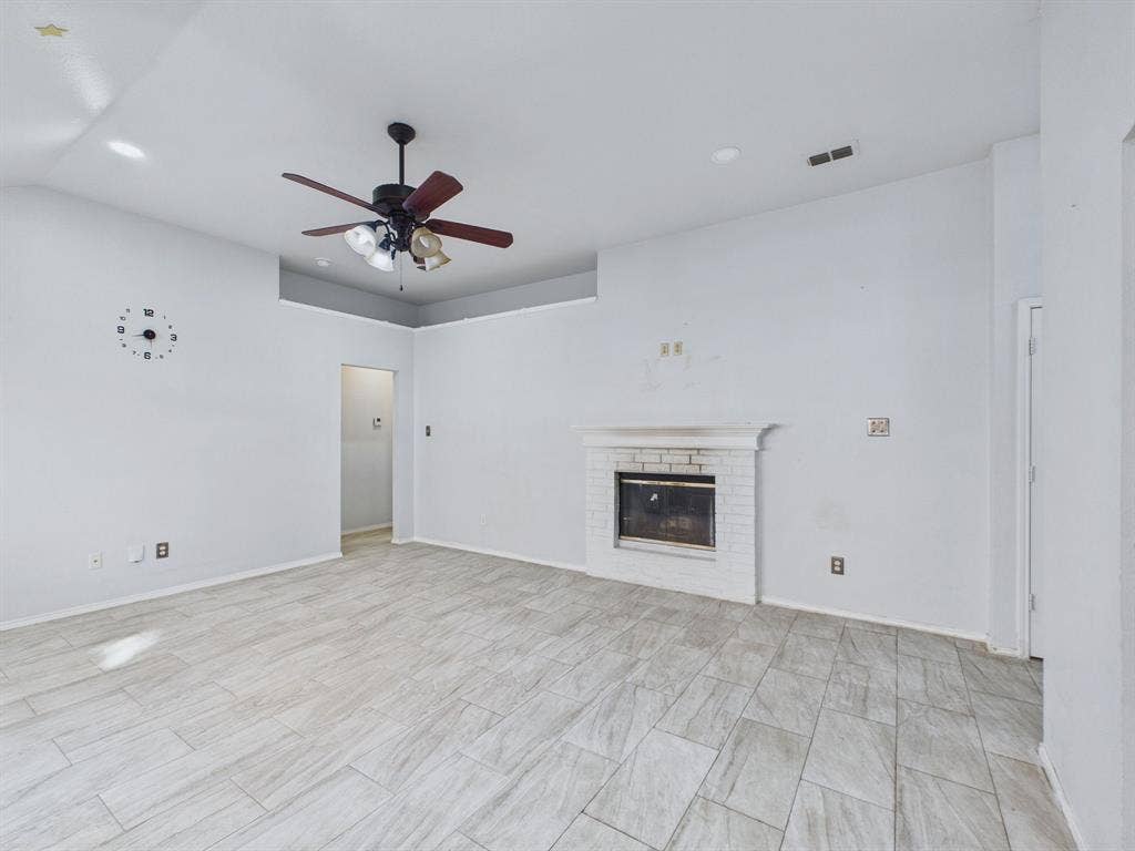 Living space featuring tray ceiling, recessed lighting, tile flooring, and a fireplace with a white brick surround