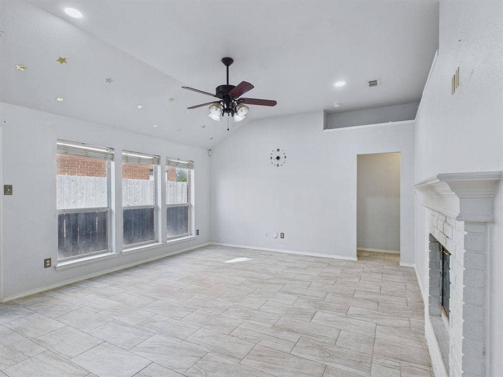 Vaulted ceilings featuring recessed lighting and a central ceiling fan, large windows, tile flooring, and a floor-to-ceiling painted brick fireplace