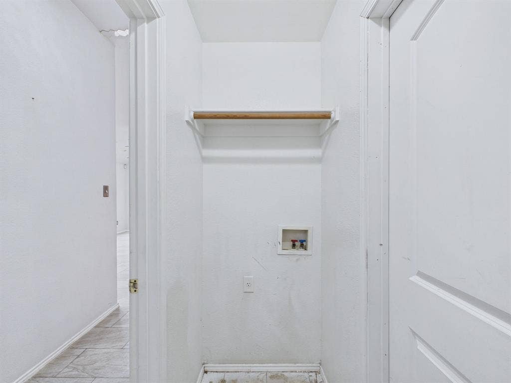 Utility closet featuring a recessed plumbing connection box, electrical outlet, and built-in overhead shelf with integrated garment rod