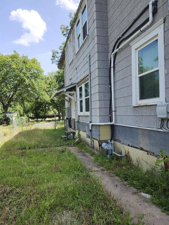 Exterior siding with white-trimmed double-hung windows, concrete walkway, and metal door awning