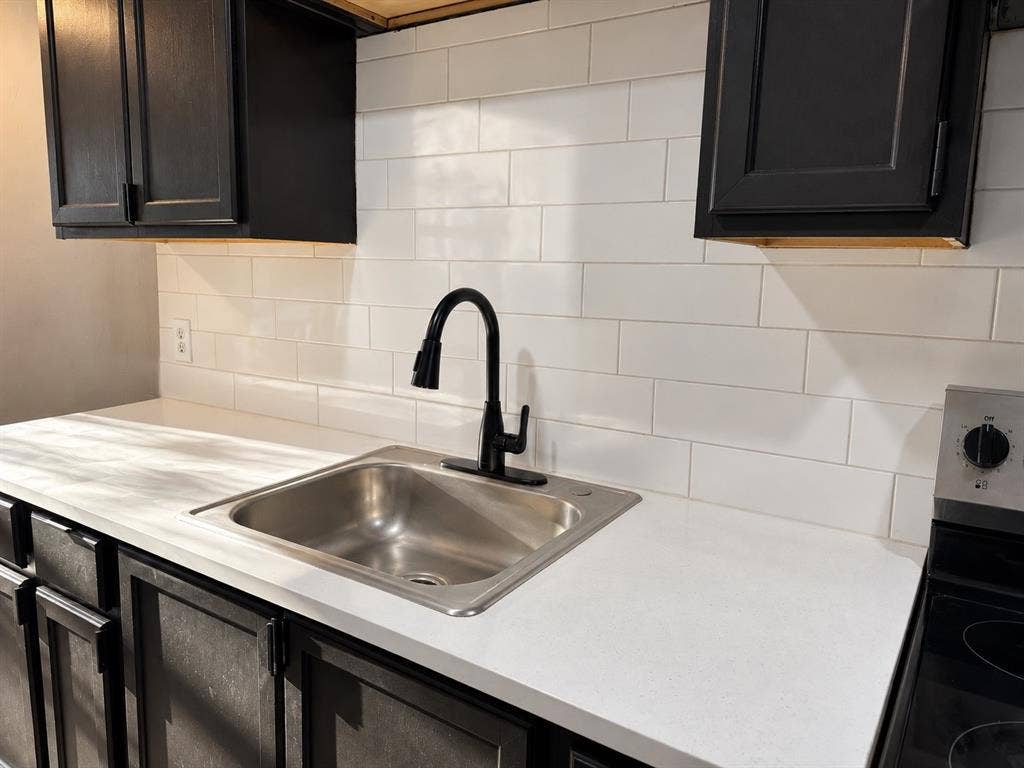 1817 N Alexander Street, Sherman, TX 75092 Functional kitchen featuring dark cabinetry, light countertops, and a classic subway tile backsplash.