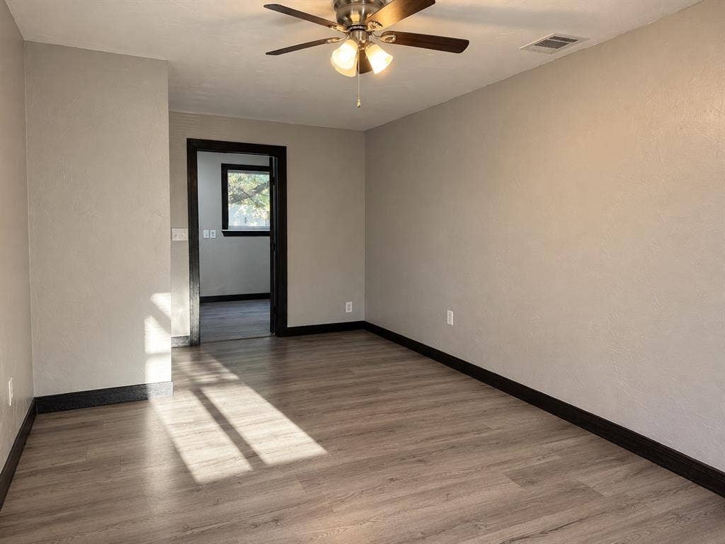 1817 N Alexander Street, Sherman, TX 75092 Spacious primary bedroom with neutral finishes and wood-look flooring.