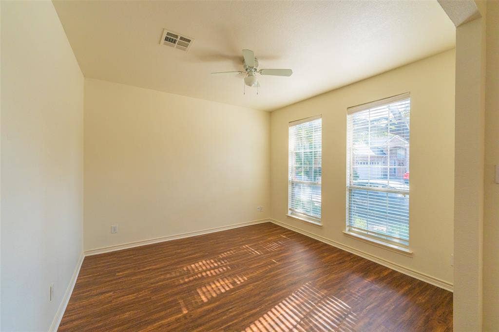 Interior room featuring wood-finish flooring, two large windows, and a ceiling-mounted fan with integrated lighting