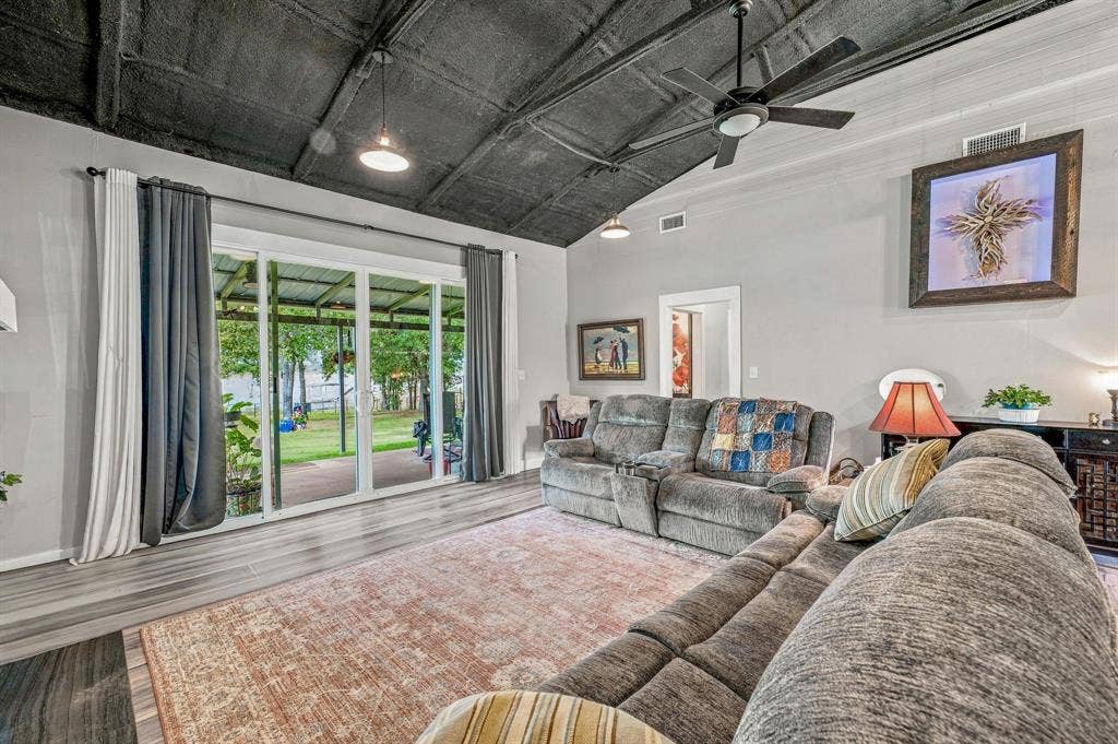 1579 Eastside Lake Road, Graham, TX 76450 Vaulted ceiling with dark finish, wood-finish flooring, sliding glass doors, and ceiling fan with integrated lighting