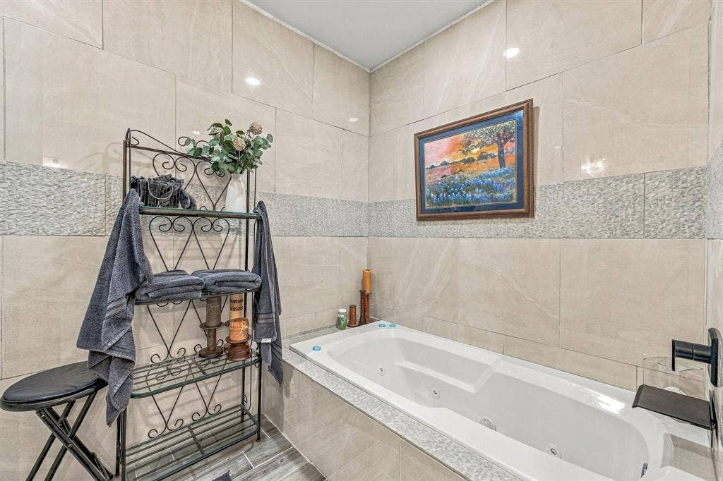 1579 Eastside Lake Road, Graham, TX 76450 Soaking tub with integrated jetted system, large-format neutral wall tiling, decorative mosaic tile inlay, and wall-mounted matte black faucet