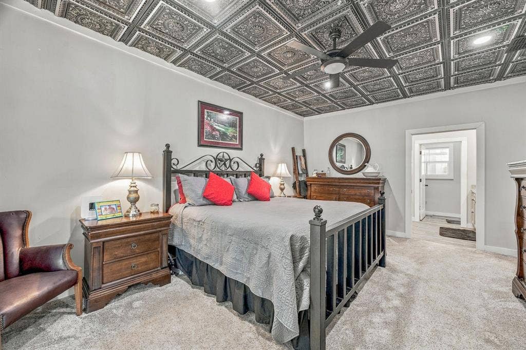 1579 Eastside Lake Road, Graham, TX 76450 Decorative coffered ceiling with intricate tin-style tiles, matte black ceiling fan, and neutral wall-to-wall carpeting