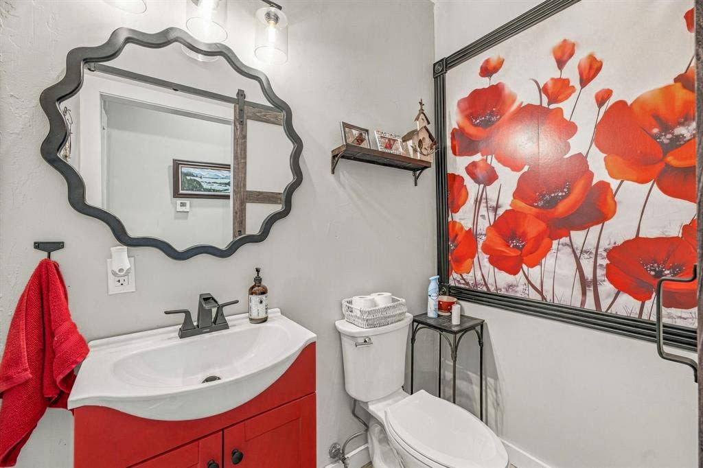 1579 Eastside Lake Road, Graham, TX 76450 Half Bath off Living area for quests with vanity featuring a curved sink basin and matte black faucet, scalloped wall mirror, and three-light overhead fixture