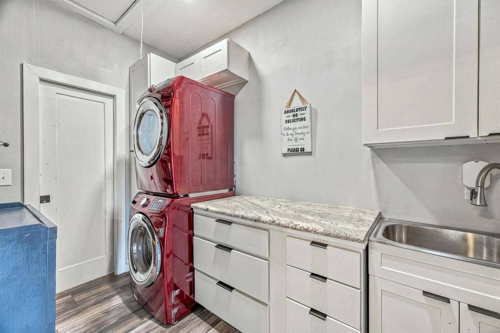 1579 Eastside Lake Road, Graham, TX 76450 White Shaker-style cabinetry featuring matte black hardware, stone-finish countertops, stainless steel drop-in sink, high-arc faucet, and wood-finish flooring. Stacked washer/dyer negotiable.