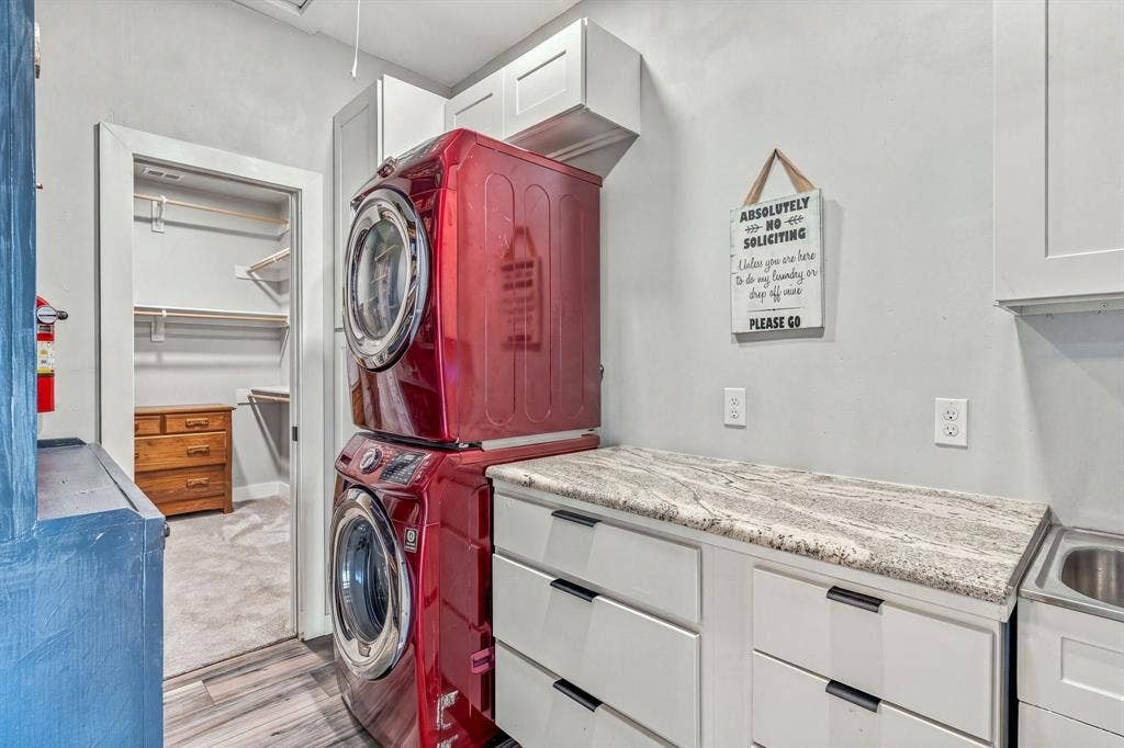1579 Eastside Lake Road, Graham, TX 76450 Utility room connects to the walk-in bedroom closet features granite-surface countertops, custom shaker-style cabinetry, overhead storage units, and an integrated stainless steel sink