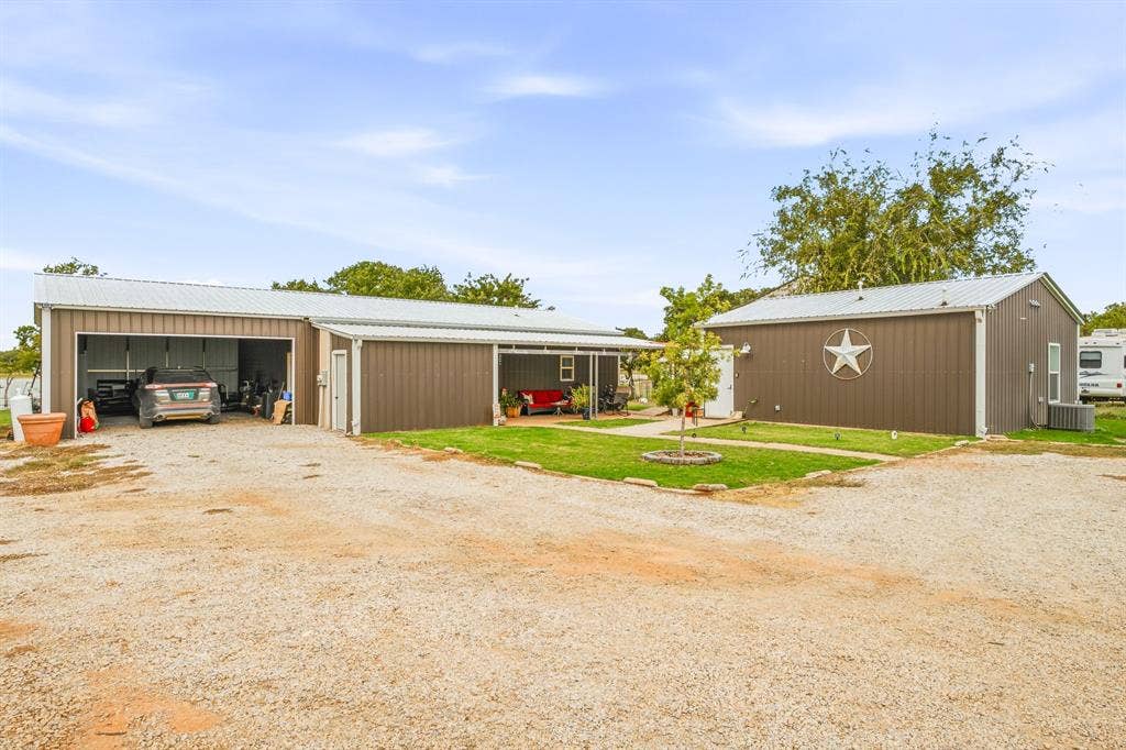 1579 Eastside Lake Road, Graham, TX 76450 Metal-sided exterior structures featuring a covered front porch, gravel driveway, and attached garage space