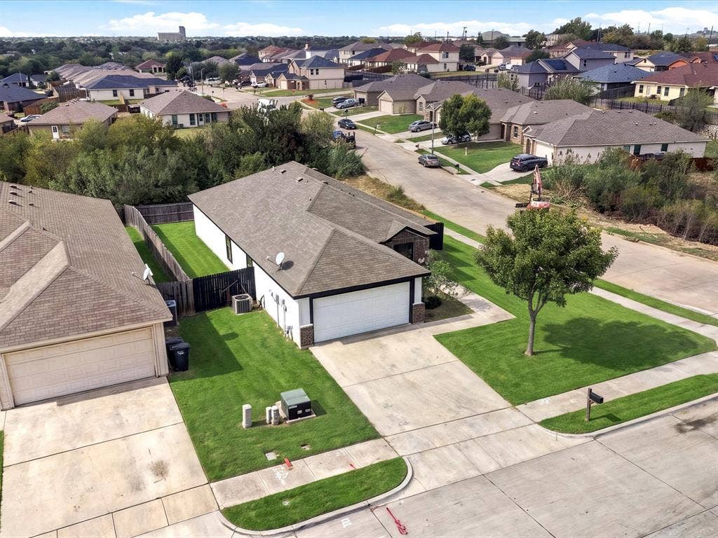 Single-story residence featuring a shingled roof, attached two-car garage, concrete driveway, and a fenced backyard