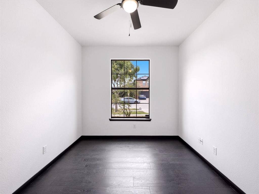 Room featuring wood-finish flooring, dark-framed grid window, and ceiling fan with integrated lighting