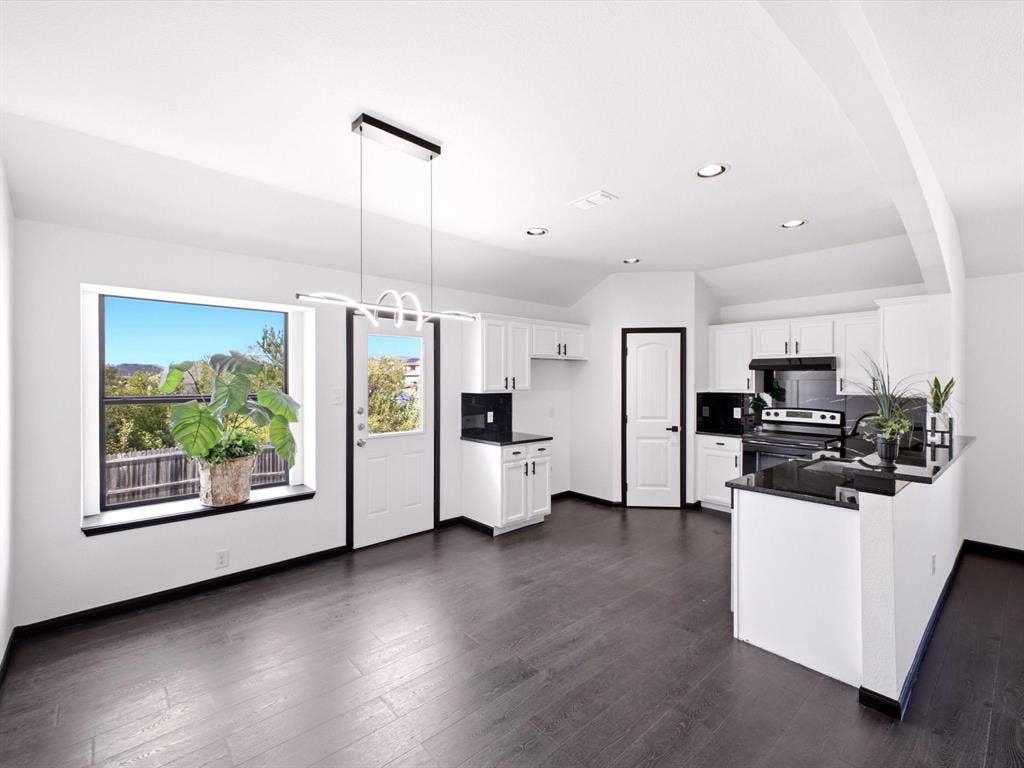 Kitchen featuring dark wood-finish flooring, white cabinetry, black countertops, a picture window, and a modern geometric pendant light fixture