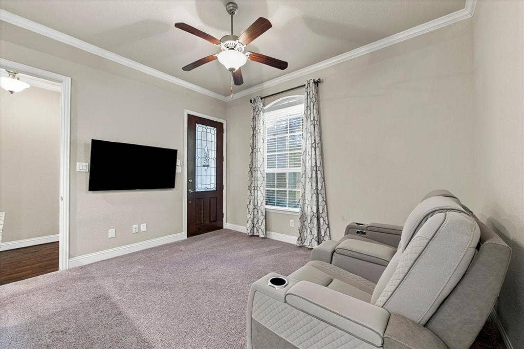 1455 Corrara Drive, Rockwall, TX 75032 Suite Sitting Room features an arched-top window, a private exterior entry door with decorative glass, and a doorway connecting to the main foyer. Carpet flooring extends throughout, transitioning to wood in the foyer.