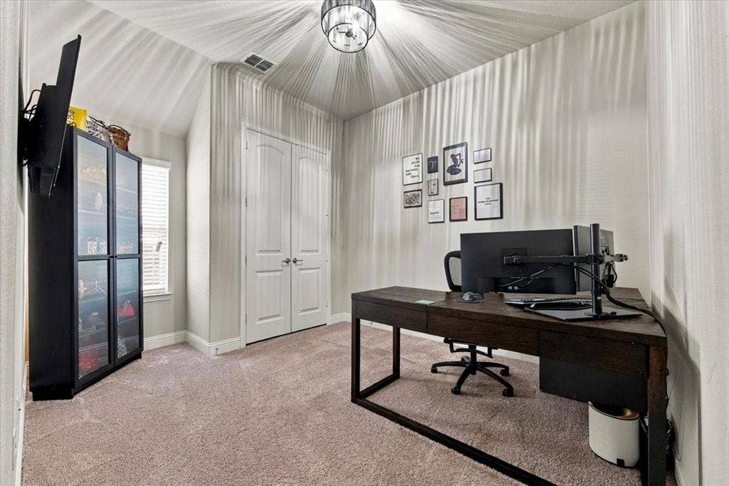1455 Corrara Drive, Rockwall, TX 75032 Secondary Bedroom features a vaulted ceiling with a drum-style light fixture, a double-door closet, and a window. Carpet flooring extends throughout.