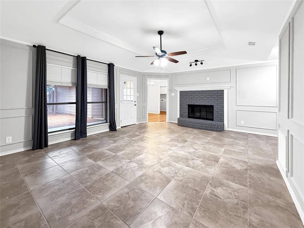 305 N Cottonbelt Avenue, Wylie, TX 75098 Living area featuring large-format tile flooring, a painted brick fireplace with mantel, recessed tray ceiling, decorative wall molding, and a central ceiling fan
