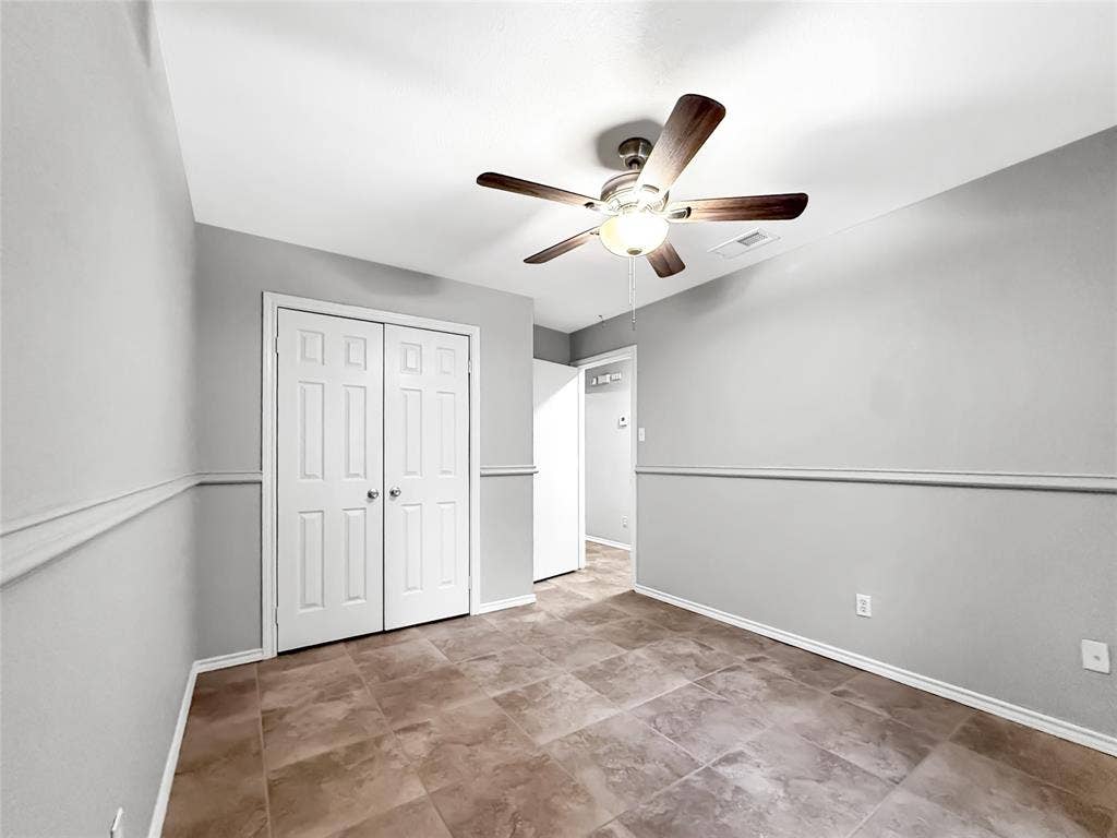 305 N Cottonbelt Avenue, Wylie, TX 75098 Interior room featuring large-format tile flooring, chair rail molding, ceiling-mounted light fixture with fan, and double-door closet